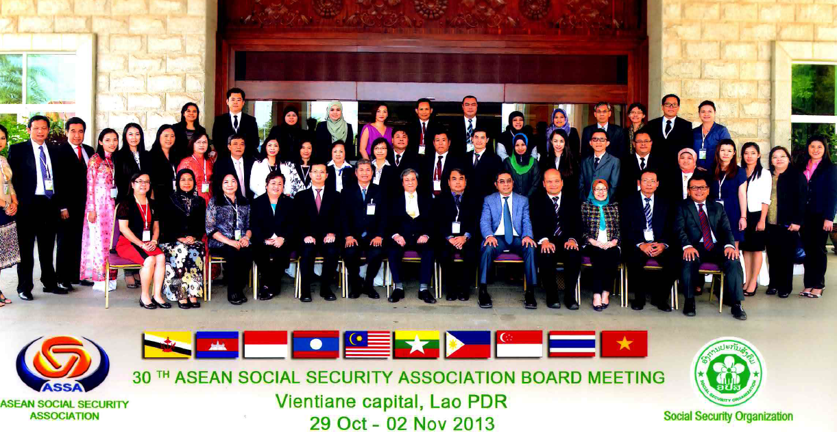 A large group of delegates pose for a formal group photograph at the 30th ASEAN Social Security Association (ASSA) Board Meeting held in Vientiane, Lao PDR from 29 October to 2 November 2013. The participants are arranged in multiple rows outside what appears to be a grand building, dressed in a mix of formal and traditional attire. The caption at the bottom of the image displays the flags of all ten ASEAN member countries, along with the ASSA logo and the logo of the host organisation, the Social Security Organization of Lao PDR.